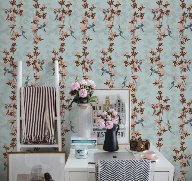 Dekoratives Zimmer mit gemusterter Tapete mit Vogel und Pflanzenmotiven, Leiterregal, Schreibtisch und Dekorationsgegenständen.