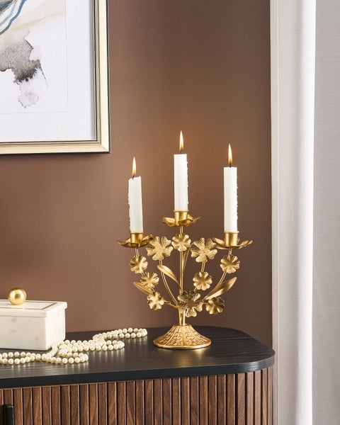 Goldfarbener Kerzenständer mit drei brennenden Kerzen auf einer Holzkommode