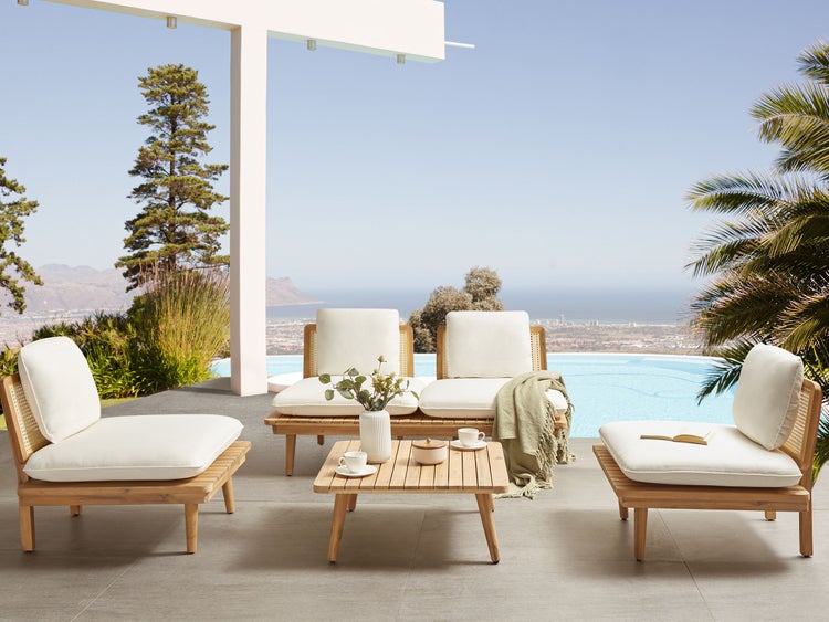 Gartenmöbel-Set mit Holzrahmen und weißen Polstern auf einer Terrasse mit Meerblick