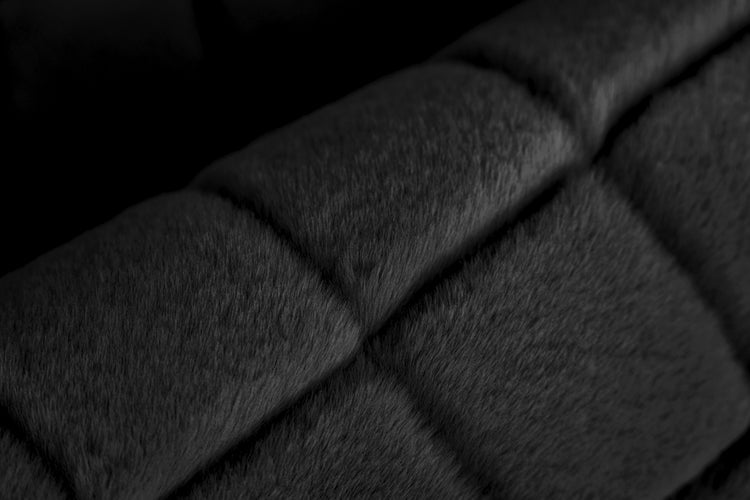 Nahaufnahme von weichem, gestepptem Kunstfell in Schwarz.