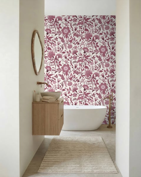 Modernes, helles Badezimmer mit floraler Mustertapete, freistehender Badewanne, Holzwaschtisch mit Aufsatzbecken und bronzefarbenen Armaturen.
