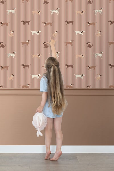 Mädchen vor Tapete mit Hundemotiv und vertikalen Streifen im Kinderzimmer