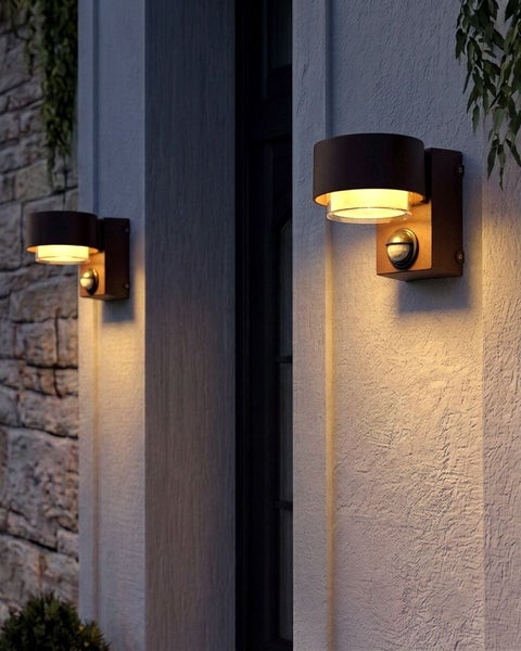 Moderne Außenwandleuchten mit Bewegungsmelder, montiert an einer weißen Hauswand, mit warmem Licht.