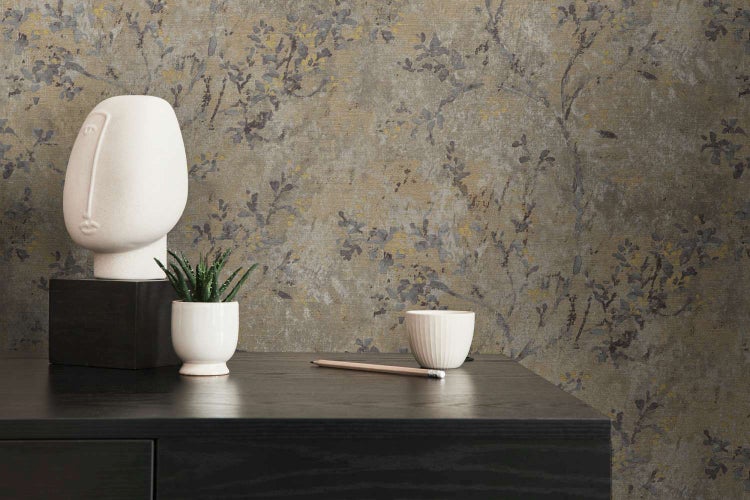 Strukturierte Vliestapete mit floralem Motiv in naturnahem Design kombiniert mit einer abstrakten Kopfskulptur auf einem dunklen Tisch.