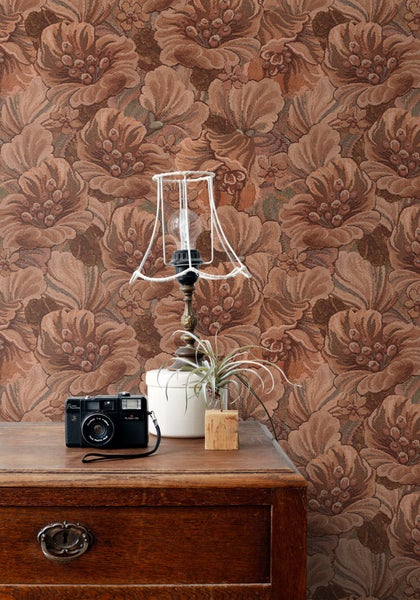Dekoratives Zimmer mit geblümter Tapete, Lampe und Holzkommode