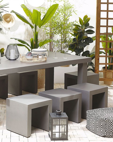 Grauer Gartentisch mit Hockern und dekorativen Elementen im Außenbereich