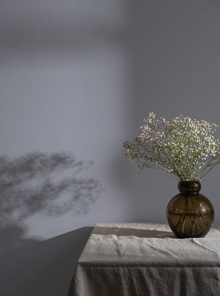Stillleben mit Schleierkraut in brauner Glasvase auf Tischdecke