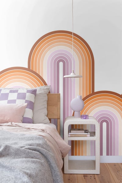 Schlafzimmer mit Bett, Nachttisch und Wandgestaltung mit Regenbogenmuster