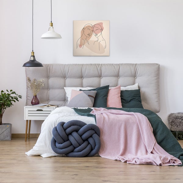Schlafzimmer mit Bett, Kissen, Decken und einem gerahmten Kunstdruck an der Wand