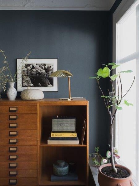 Helles Zimmer mit gemusterter Tapete, Ofen, Esstisch und Stühlen.