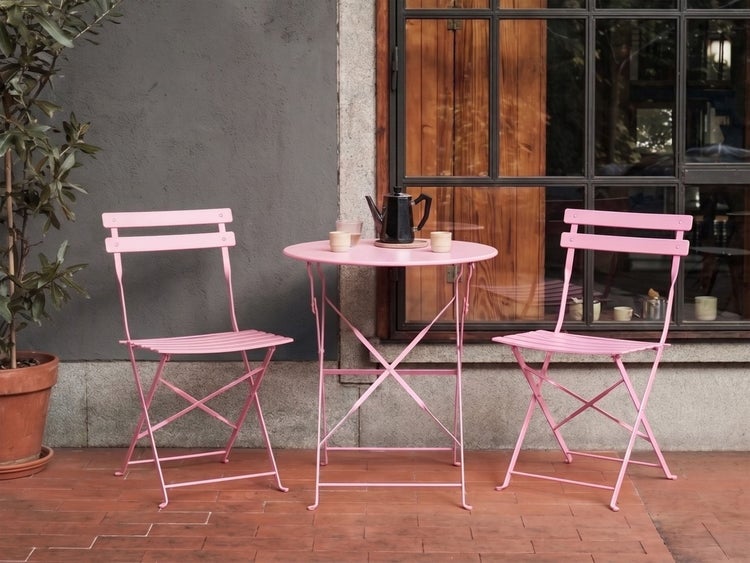 Rosa Bistro-Set mit rundem Klapptisch und zwei Klappstühlen aus Metall, geeignet für Balkon und Garten.