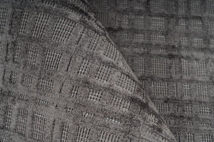 Strukturierter Teppich in Anthrazit mit geometrischem Karomuster.