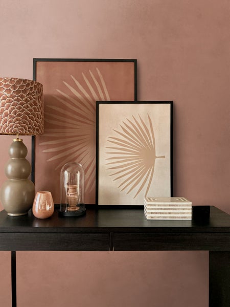 Dekoratives Stillleben mit Tischleuchte, Bildern, Glasglocke und Schmuckschatulle auf einem Tisch