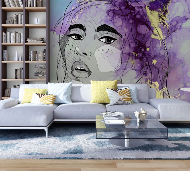 Helles Wohnzimmer mit großem Wandbild eines Frauengesichts, grauem Ecksofa, Glastisch, gemustertem Teppich und hohem Bücherregal aus Holz.