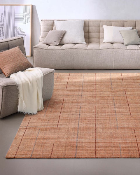 Moderner terracottafarbener Teppich mit dezentem Karomuster in einem hellen Wohnzimmer mit beigem Sofa und Sessel.