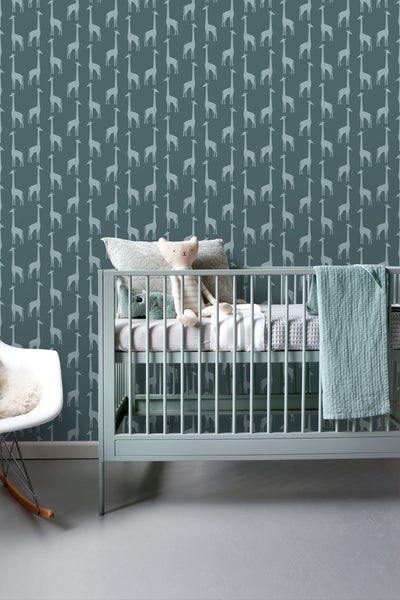 Kinderzimmer mit Gitterbett, Schaukelstuhl und Tapete mit Giraffenmuster