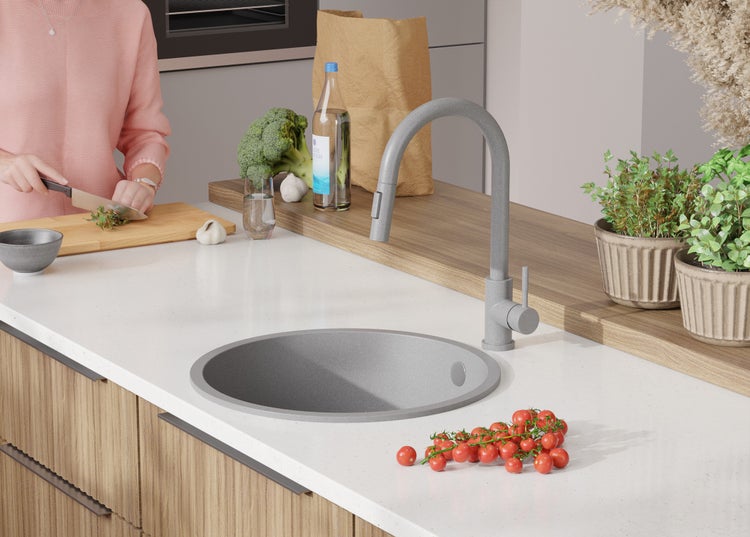 Küchenszene mit Spüle, Armatur und Lebensmitteln auf einer Arbeitsplatte.