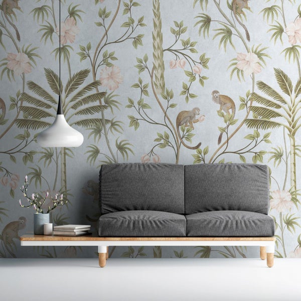 Graues Sofa vor floraler Tapete mit Affenmotiven in einem Wohnzimmer