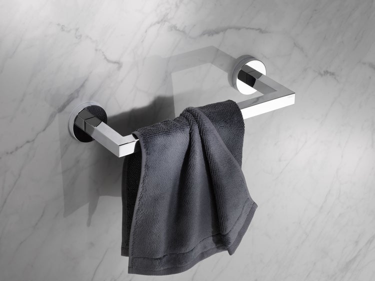 Ein moderner Handtuchhalter aus Metall mit eckigem Design, der an einer marmorierten Wand montiert ist und ein aufgehängtes Handtuch trägt.