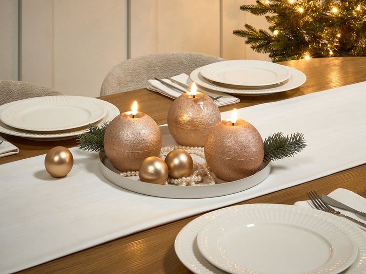 Festlich gedeckter Tisch mit Kerzen, Weihnachtskugeln und Geschirr