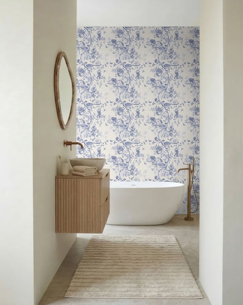 Helles, modernes Badezimmer mit freistehender Badewanne, hölzernem Waschtisch, Aufsatzwaschbecken und Wandtapete mit floralem Vogelmuster.