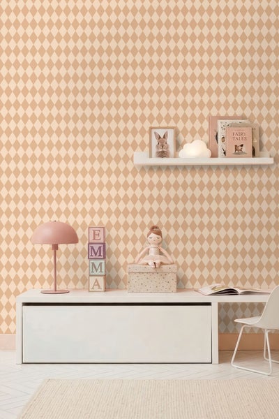 Vliestapete mit Harlekinmuster in Beige und Creme in einem hell eingerichteten Kinderzimmer mit weißen Möbeln und Dekoration.