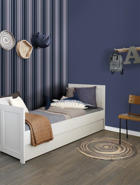 Kinderzimmer mit weißem Bett, gestreifter Tapete und dekorativen Elementen