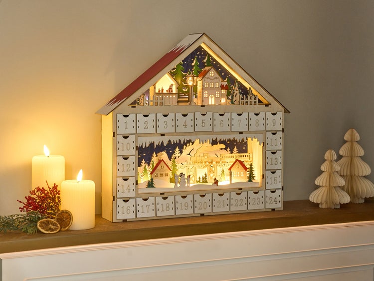Beleuchteter Adventskalender in Hausform mit 24 nummerierten Schubladen.