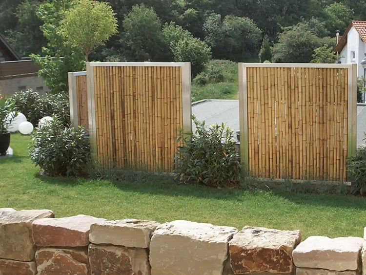 Gartenszene mit Bambuszaunelementen und Natursteinmauer