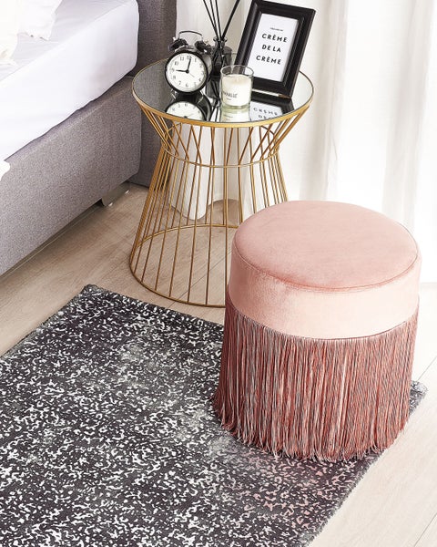 Dekoratives Schlafzimmerarrangement mit Teppich, Hocker und Beistelltisch