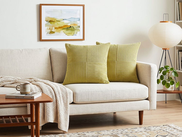 Zwei quadratische Kissen mit strukturierter Cordoberfläche auf einem hellen Sofa in einem modernen Wohnzimmer