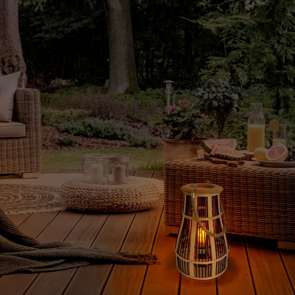 Gartenambiente mit Rattanmöbeln, Dekorationen und einer Laterne