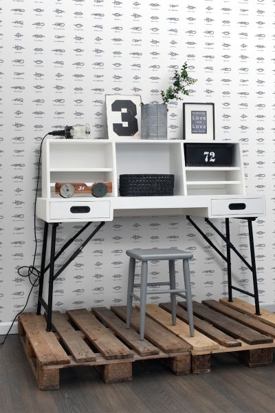 Dekoratives Arbeitszimmer mit weißem Schreibtisch, Hocker und Holzpaletten