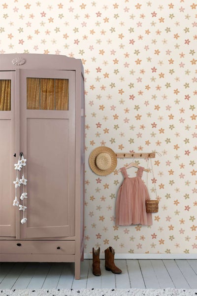 Kindertapete mit Blumenmuster vor einem Kleiderschrank mit Kinderkleidung, Hut und Stiefeln in einem Zimmer