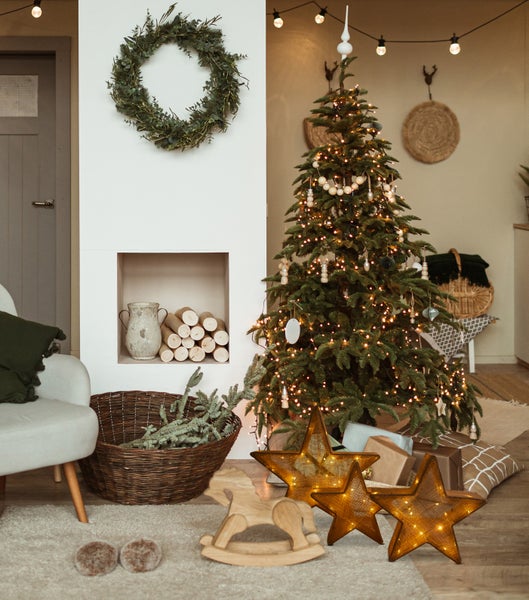 Festliche Wohnraumdekoration mit Weihnachtsbaum, Sternenlichtern und Holzspielzeug