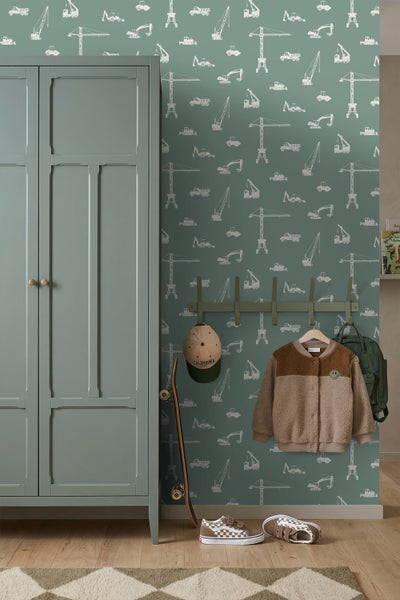 Kinderzimmer mit Tapete im Baustellen-Design, grünem Kleiderschrank, Garderobe und Holzfußboden.