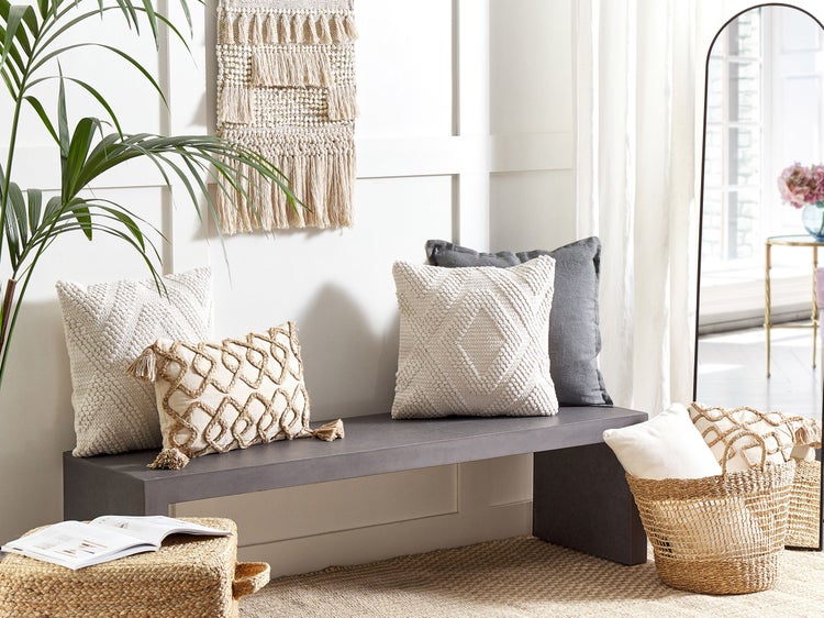 Innenraumszene mit Kissen auf einer Bank, Wandteppich und Dekoartikeln für eine gemütliche Atmosphäre