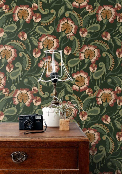 Vliestapete mit großflächigem, floralem Ornamentmuster im Vintage-Stil hinter einer Holzkommode mit Lampe und Kamera.