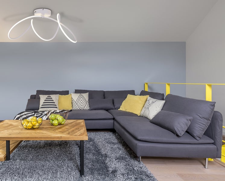 Wohnzimmer mit grauer Eckcouch, Holztisch und moderner Deckenleuchte