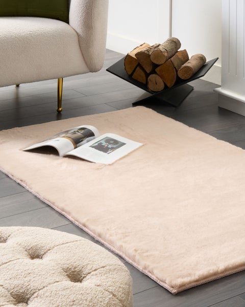 Beige Teppich im Wohnzimmer mit Sessel und Brennholz