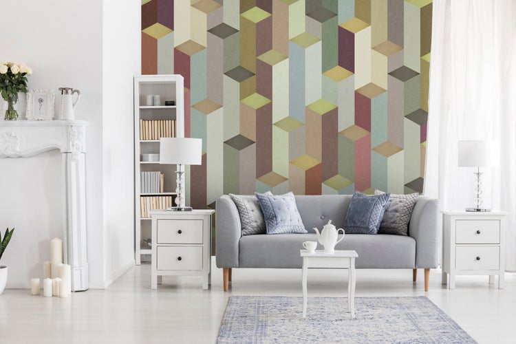 Wohnzimmer mit Sofa, Tisch, Teekanne, Bücherregal und geometrischer Tapete