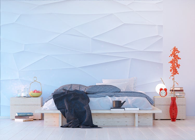Schlafzimmer mit Bett vor einer Wandtapete mit geometrischem Muster