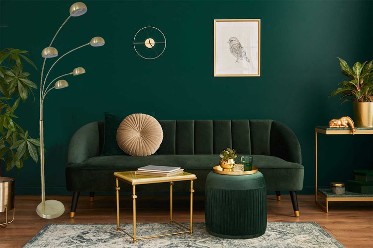 Wohnzimmer mit Sofa, Stehlampe, Couchtisch, Beistelltisch und Dekoration vor grüner Wand