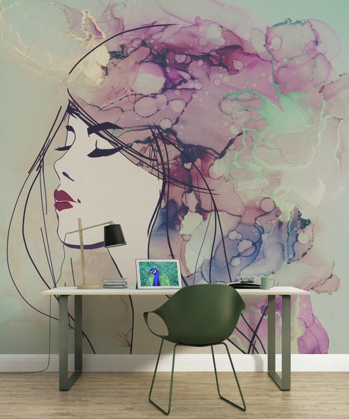 Moderne Wandgestaltung mit einer Fototapete, die ein abstraktes Frauenporträt in Aquarell-Optik zeigt, hinter einem Schreibtisch mit grünem Stuhl.
