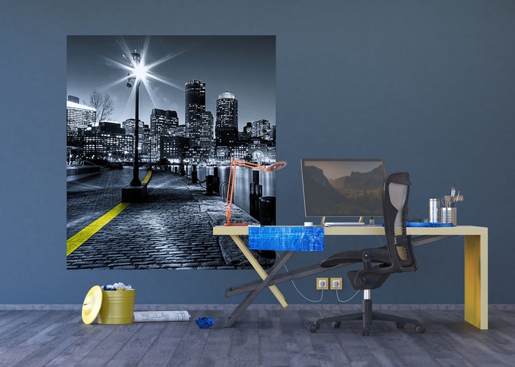 Büroszene mit Schreibtisch, Bürostuhl, Lampe, Papierkorb und gerahmtem Nachtfoto einer Stadt