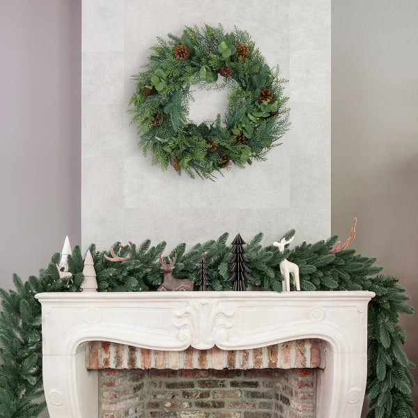 Dekorative Szene mit einem Kranz an der Wand und einer Girlande auf einem Kaminsims mit Dekorationen