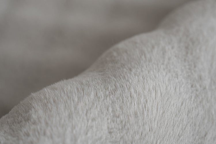 Nahaufnahme der Textur eines weichen Plüschstoffs oder Kunstfells.