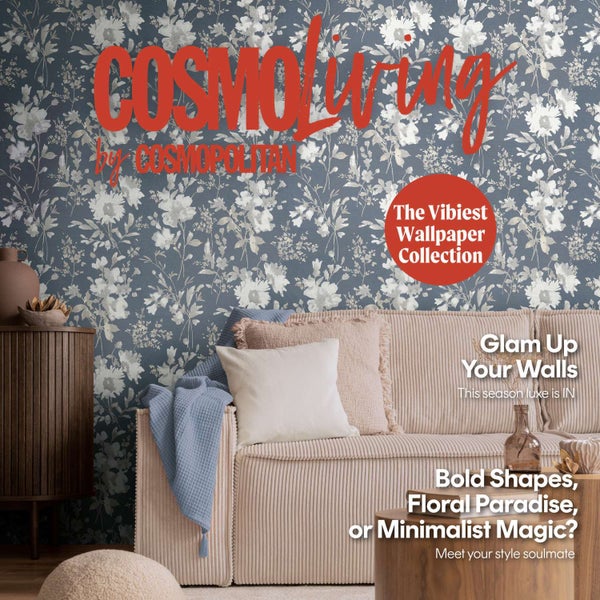 Wohnzimmer mit blumig gemusterter Vliestapete, Sofa mit Kissen und Textilien, moderner Einrichtungsstil mit floralem Design.