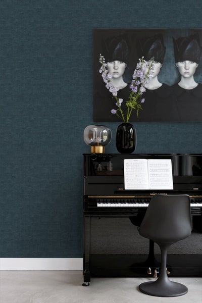 Dunkelblaue Vliestapete mit feiner Leinenstruktur in einem modernen Wohnraum mit schwarzem Klavier und Wandkunst.