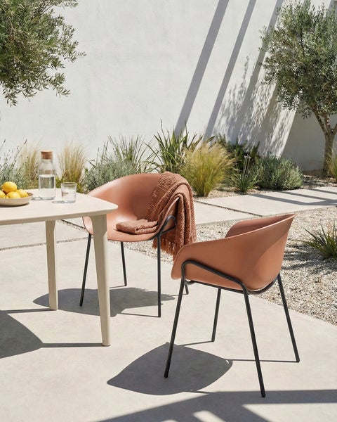 Szene im Freien mit Esstisch, Wasserflasche, Gläsern, Obstschale und zwei Armlehnstühlen